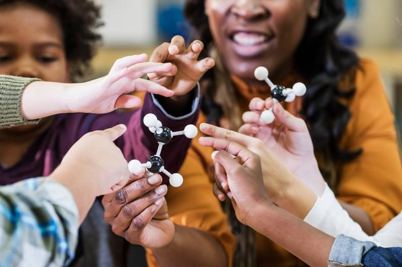 A group of people holding a molecule model

Description automatically generated